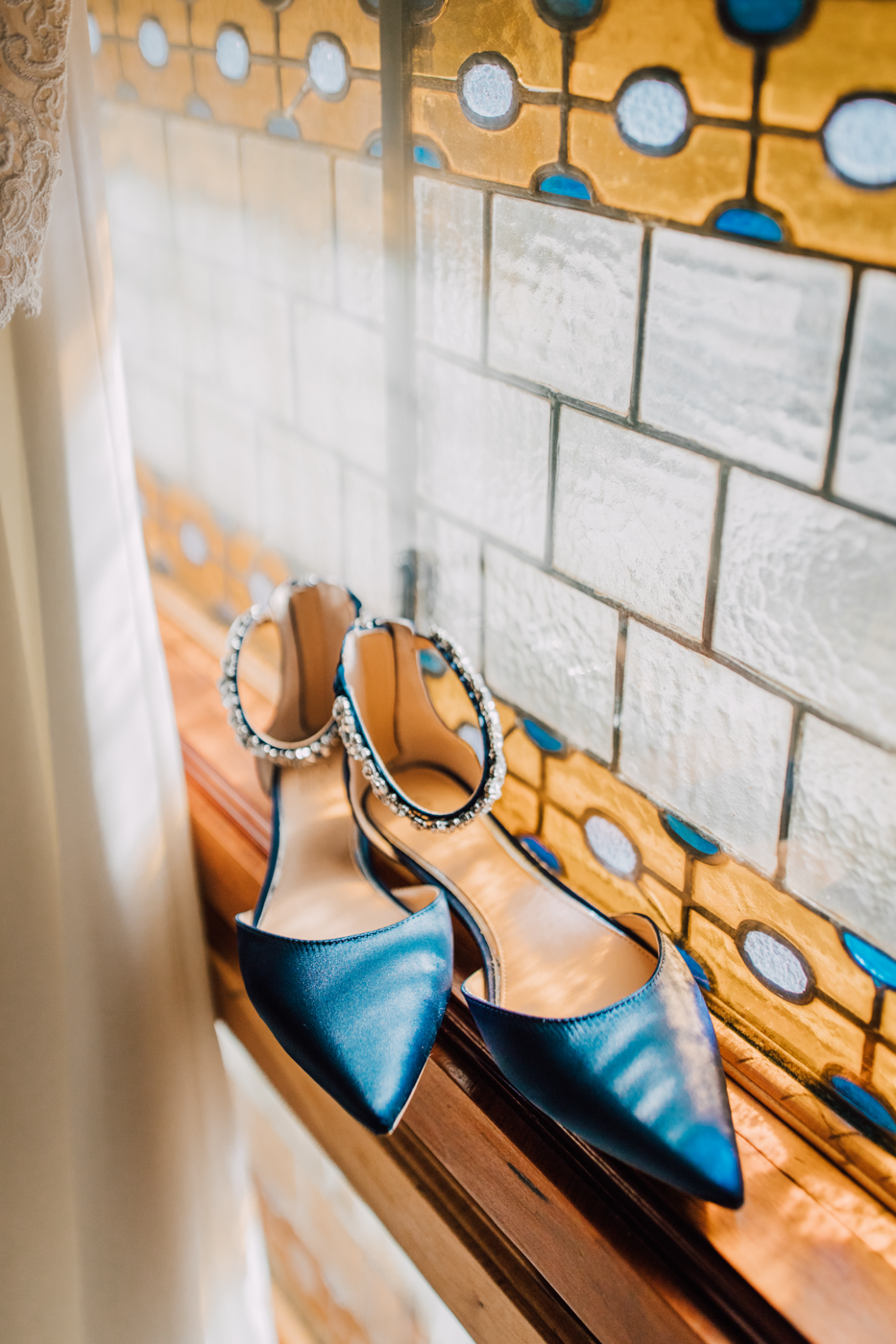  Blue wedding shoes sitting next to a stained glass window 