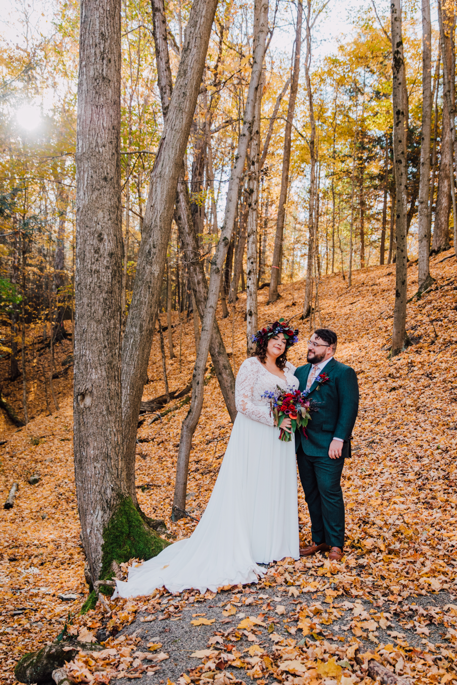  Bride and Groom pose together in the woods at New Park event venue during their moody fall wedding 