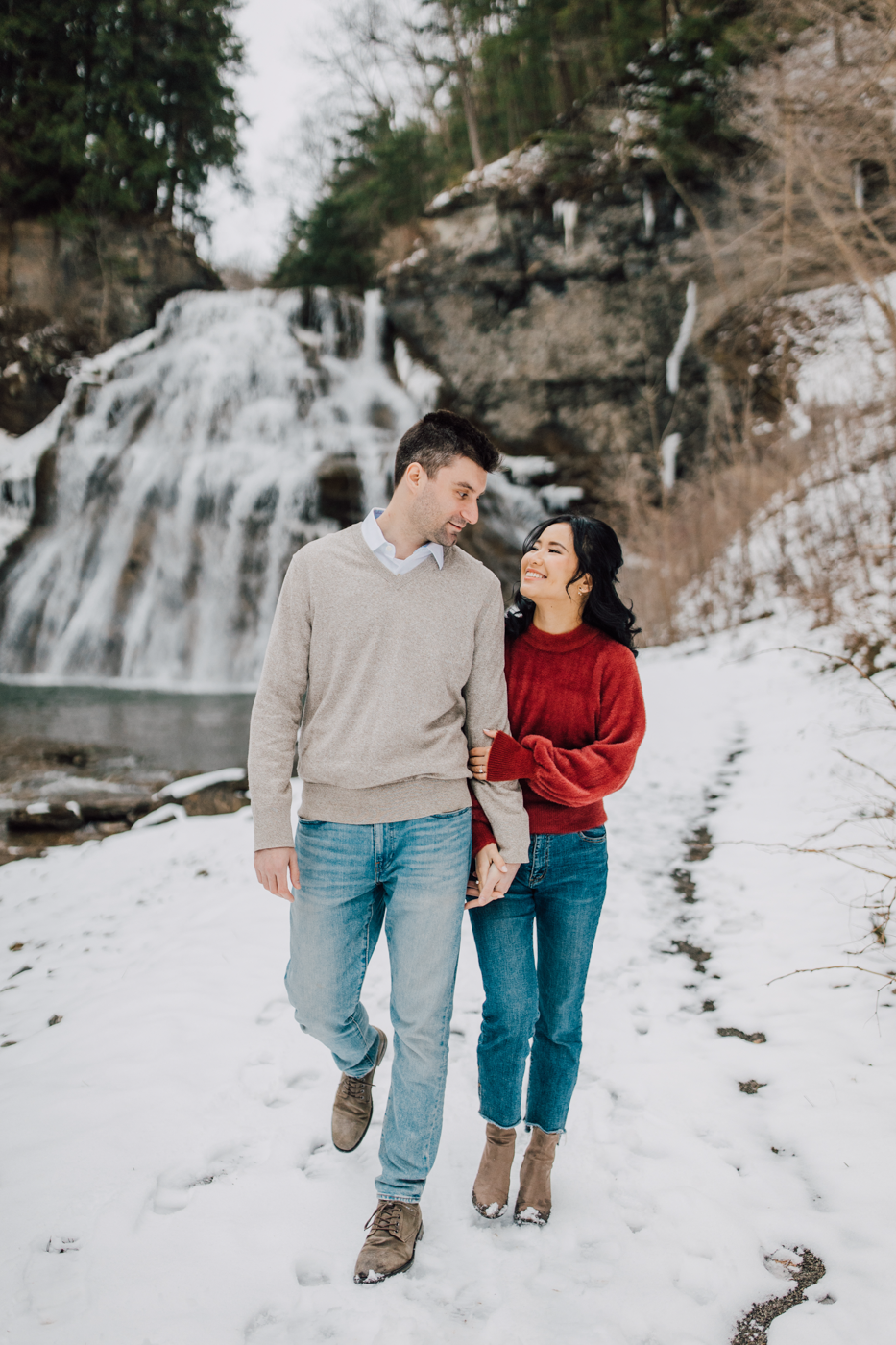  Engaged couple walk together through the snow at Delphi Falls during their winter engagement photos 