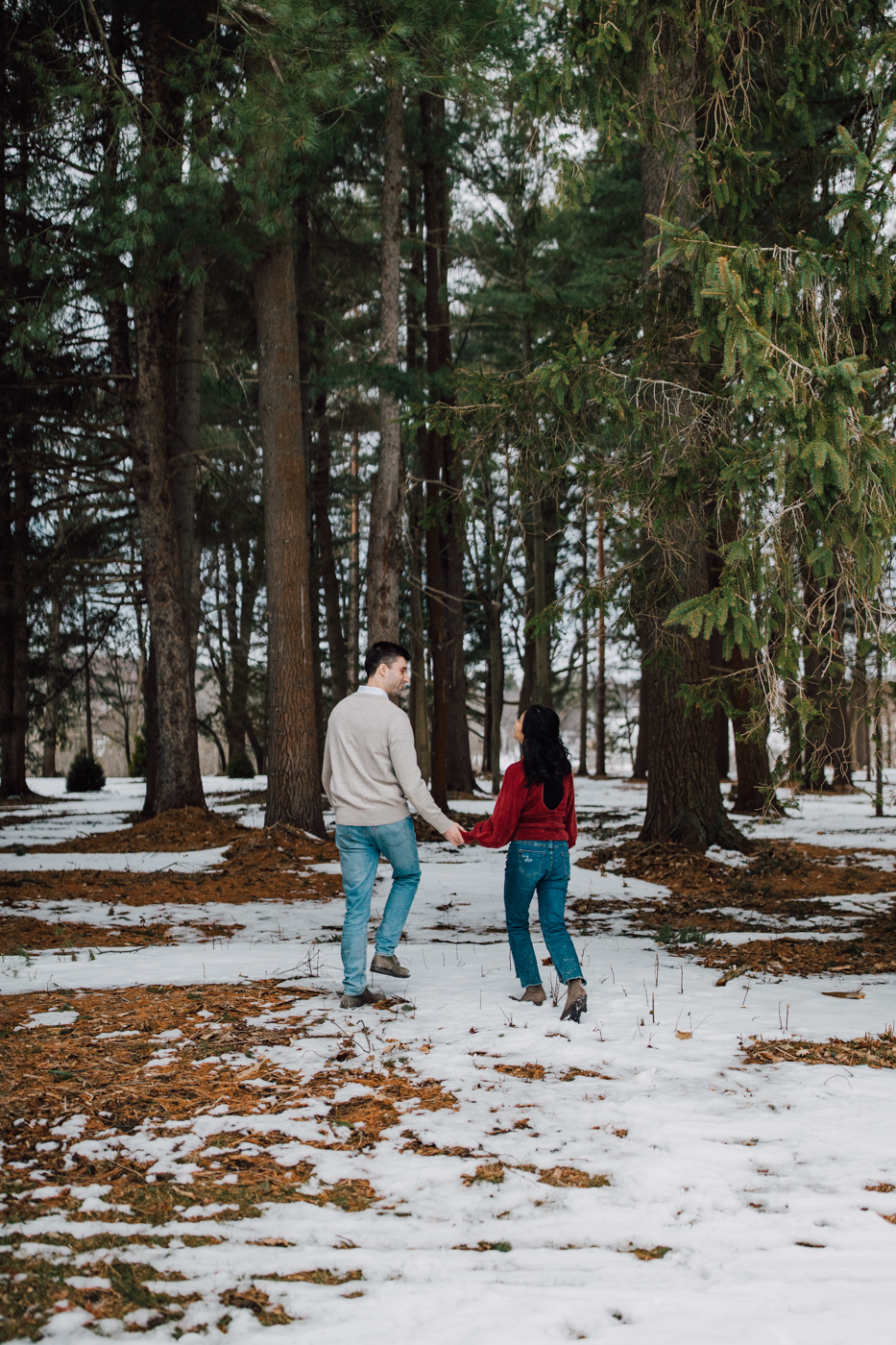  Engaged couple walks through the woods holding hands during forest engagement photos in central NY 