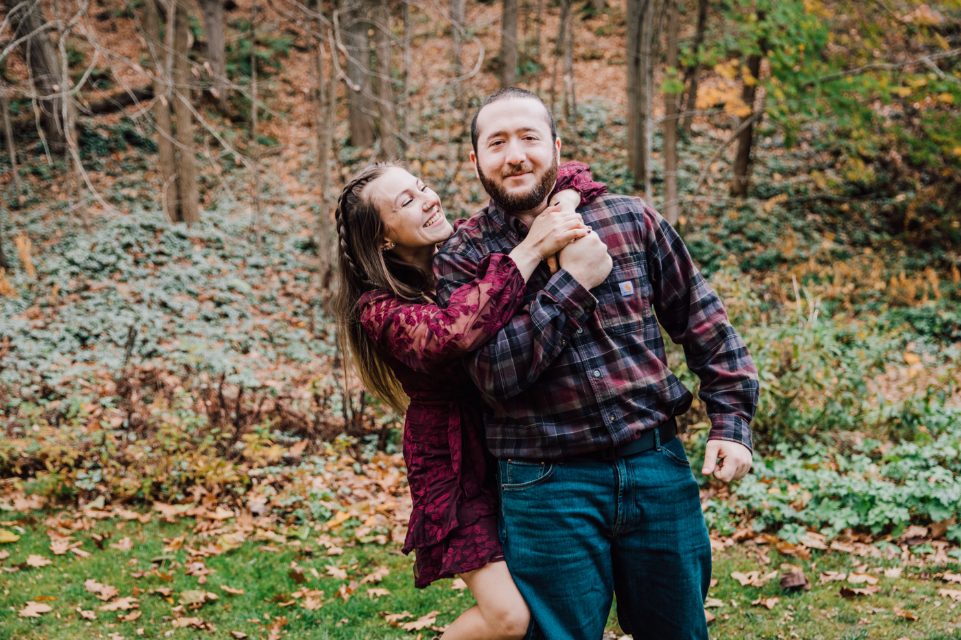  Woman wraps her arms around her fiance’s neck during their fall engagement photos at Delphi Falls county park 