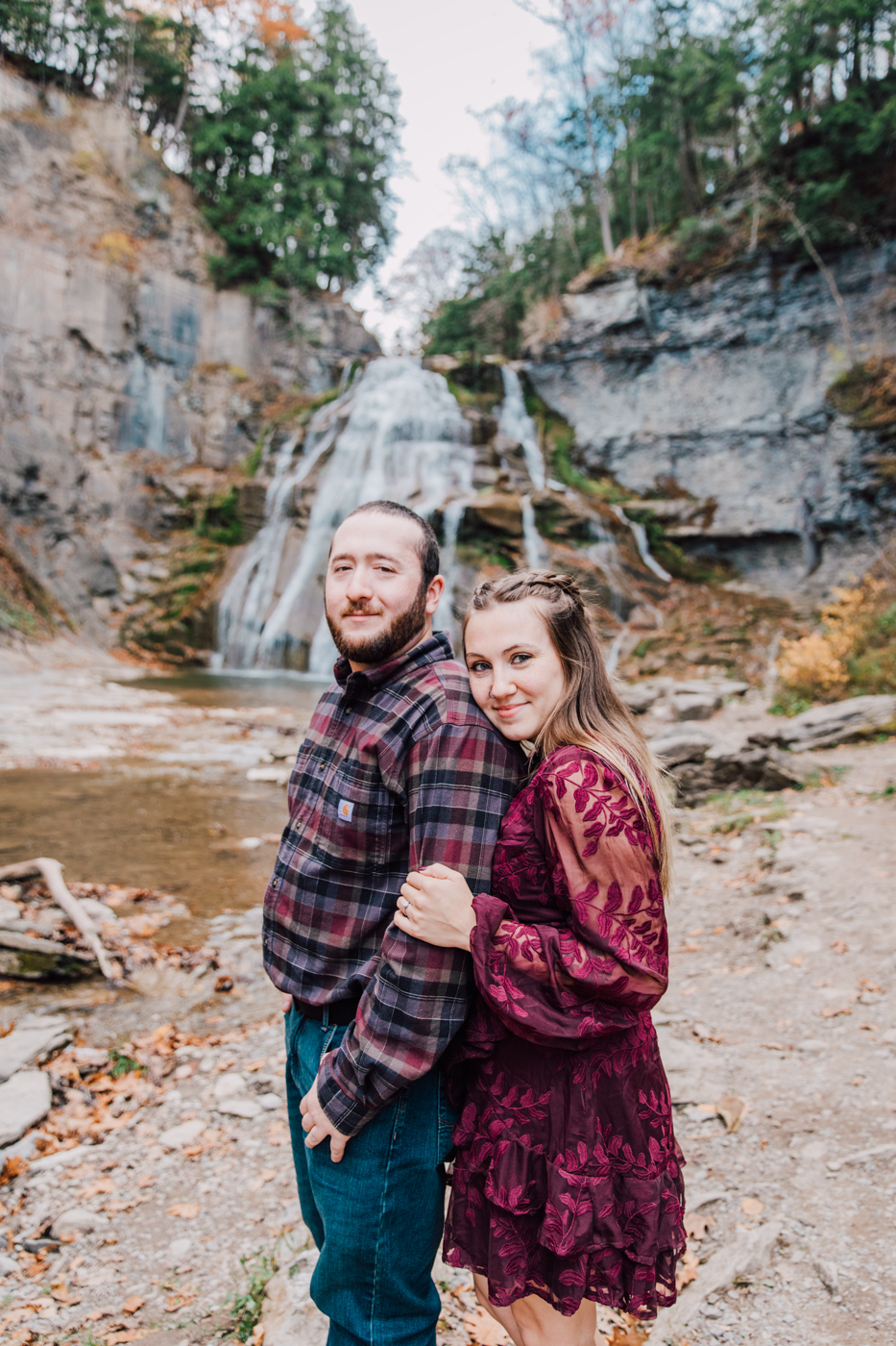  Woman hugs her fiance from behind during their waterfall photo shoot in Cazenovia NY 