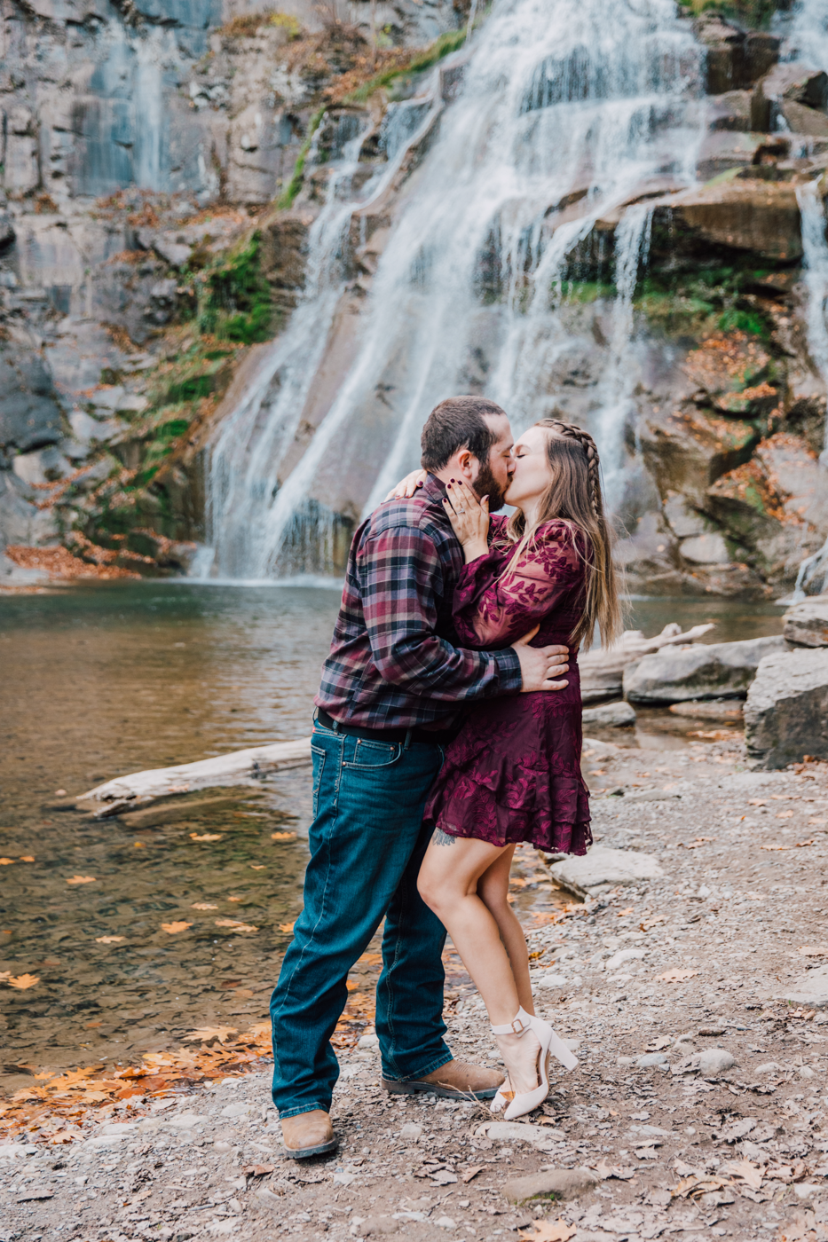  Engaged couple kisses passionately in front of a waterfall during their engagement session in Cazenovia NY 