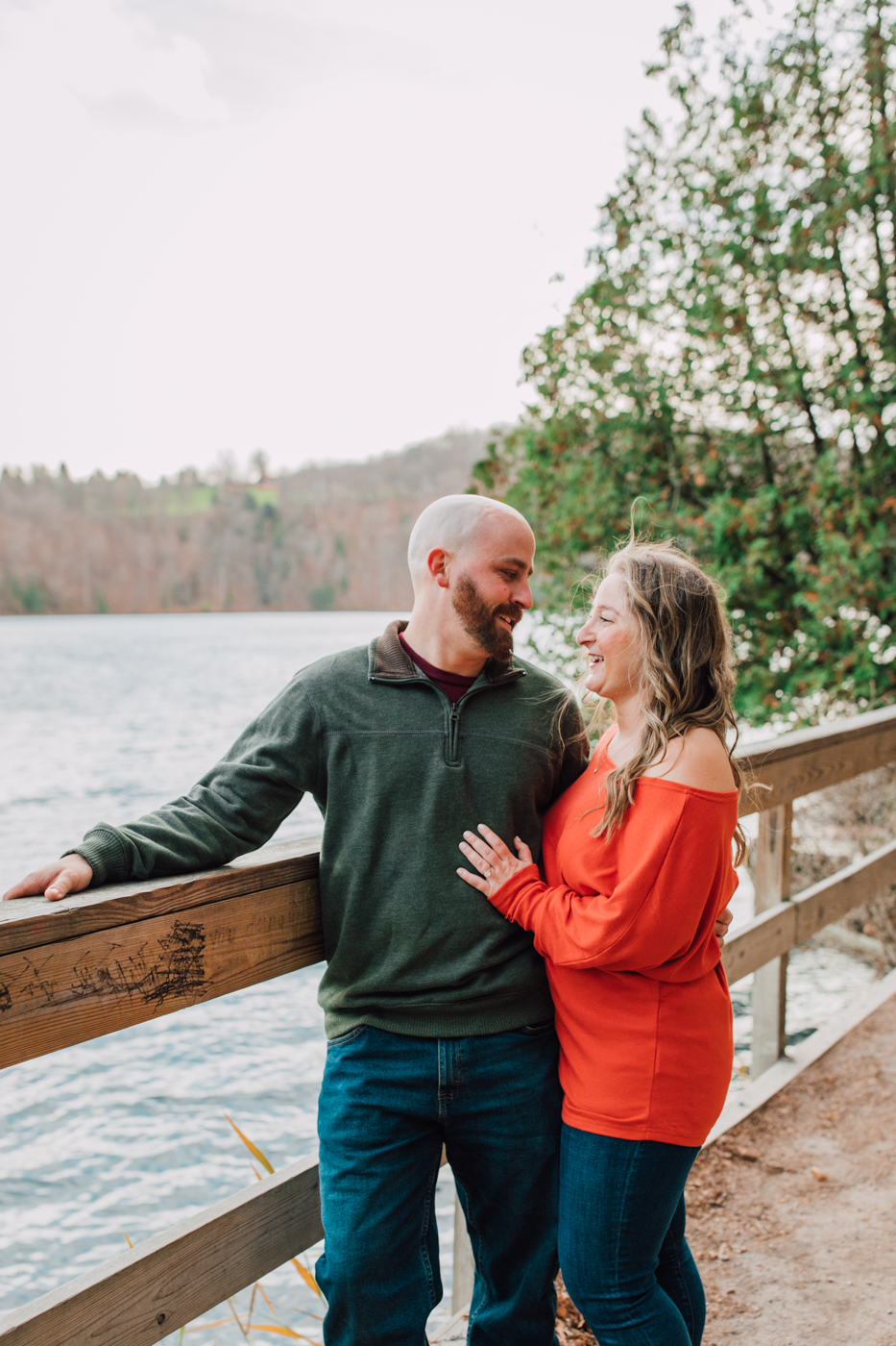  Engaged couple poses on a bridge during fall engagement photos at Green Lakes State Park 