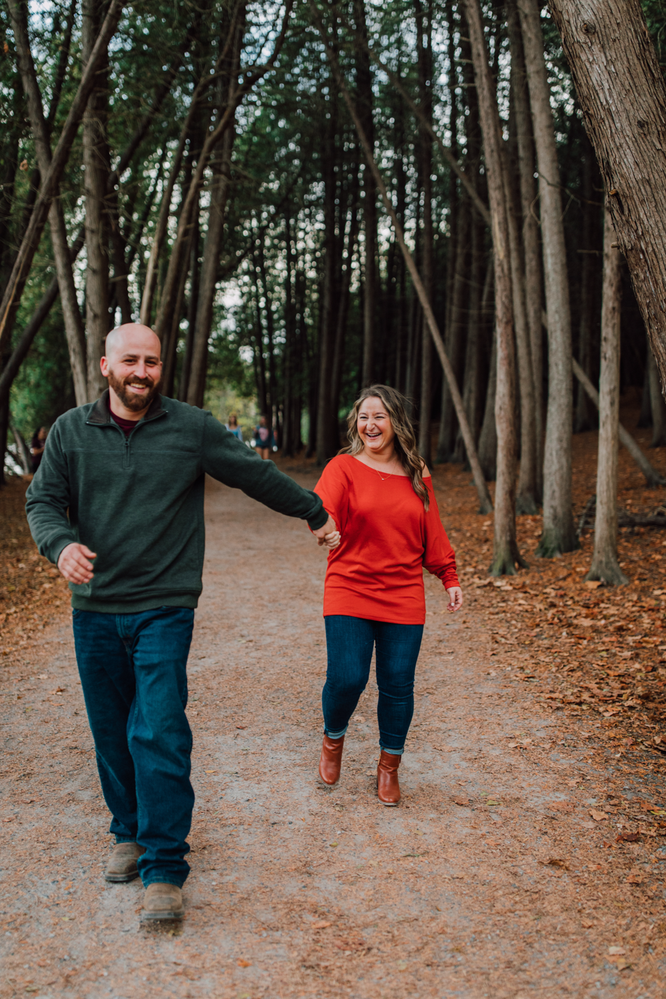  Engaged couple plays around while walking together through the woods at Green Lakes State Park 