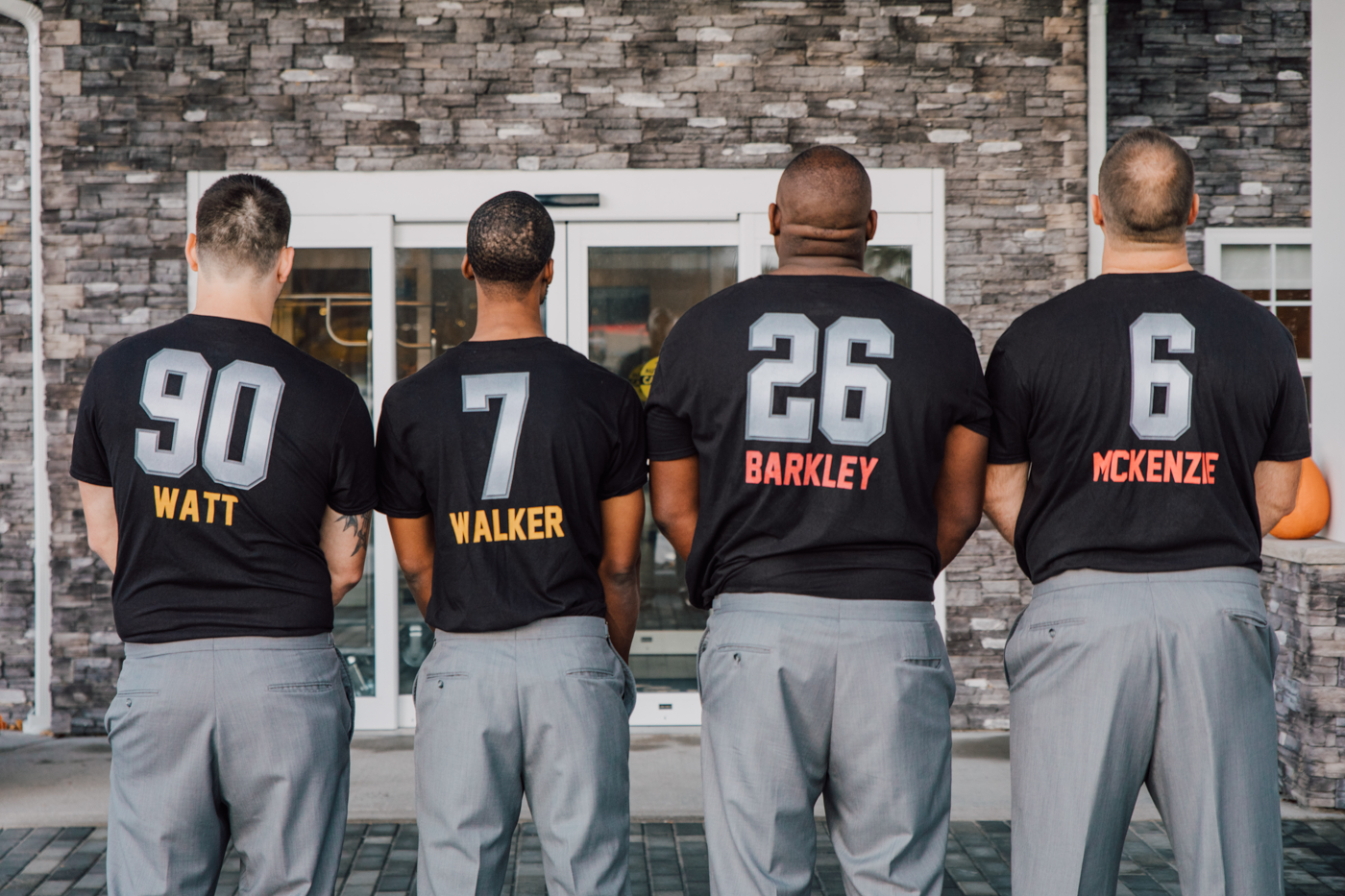  Groomsmen lined up wearing football jersey shirts with their names on the back 
