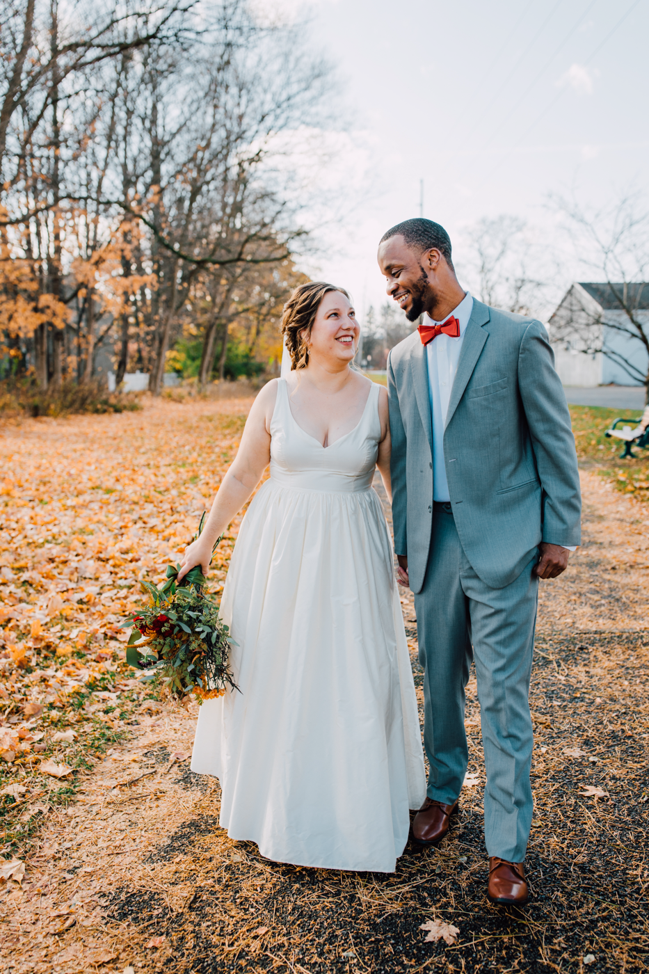  Bride and Groom walk together holding hands during their fall wedding in Central NY 