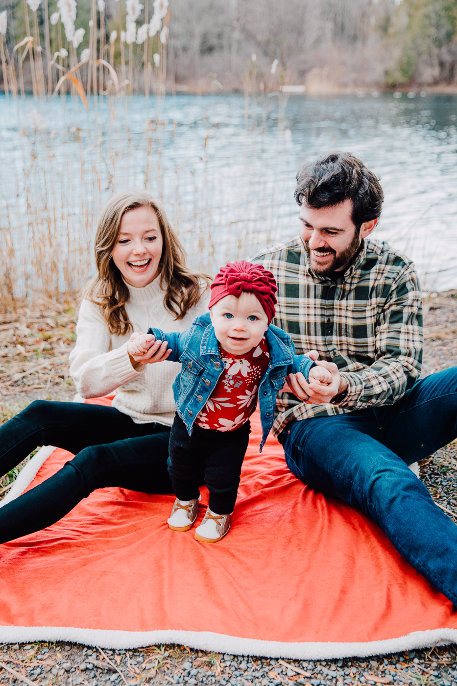  Parents sit on a blanket with their toddler during family photos with Brittany Juravich at Green Lakes State Park 
