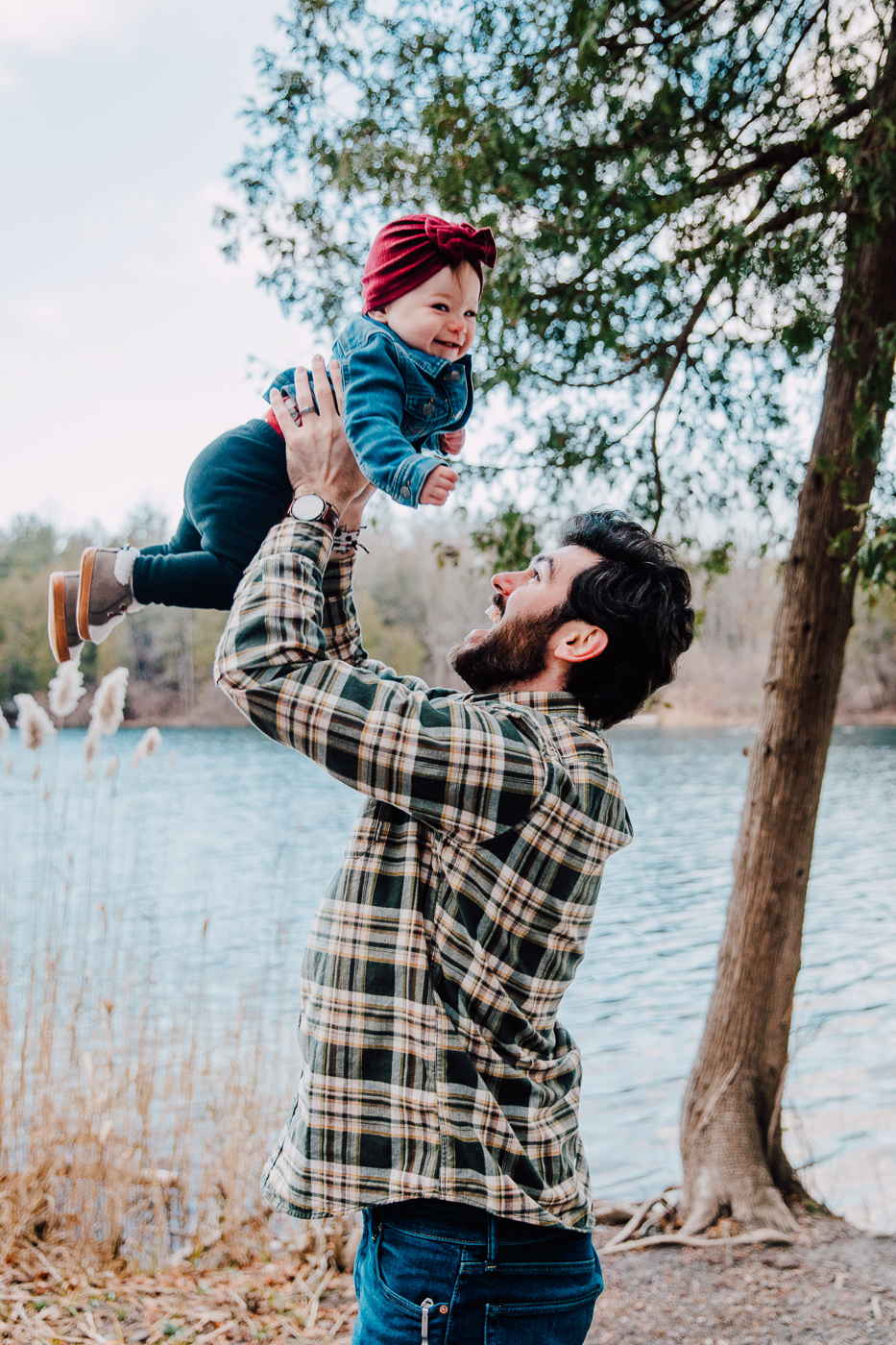  Man lifts his infant daughter in the air during family photos with Brittany Juravich at Green Lakes State Park 