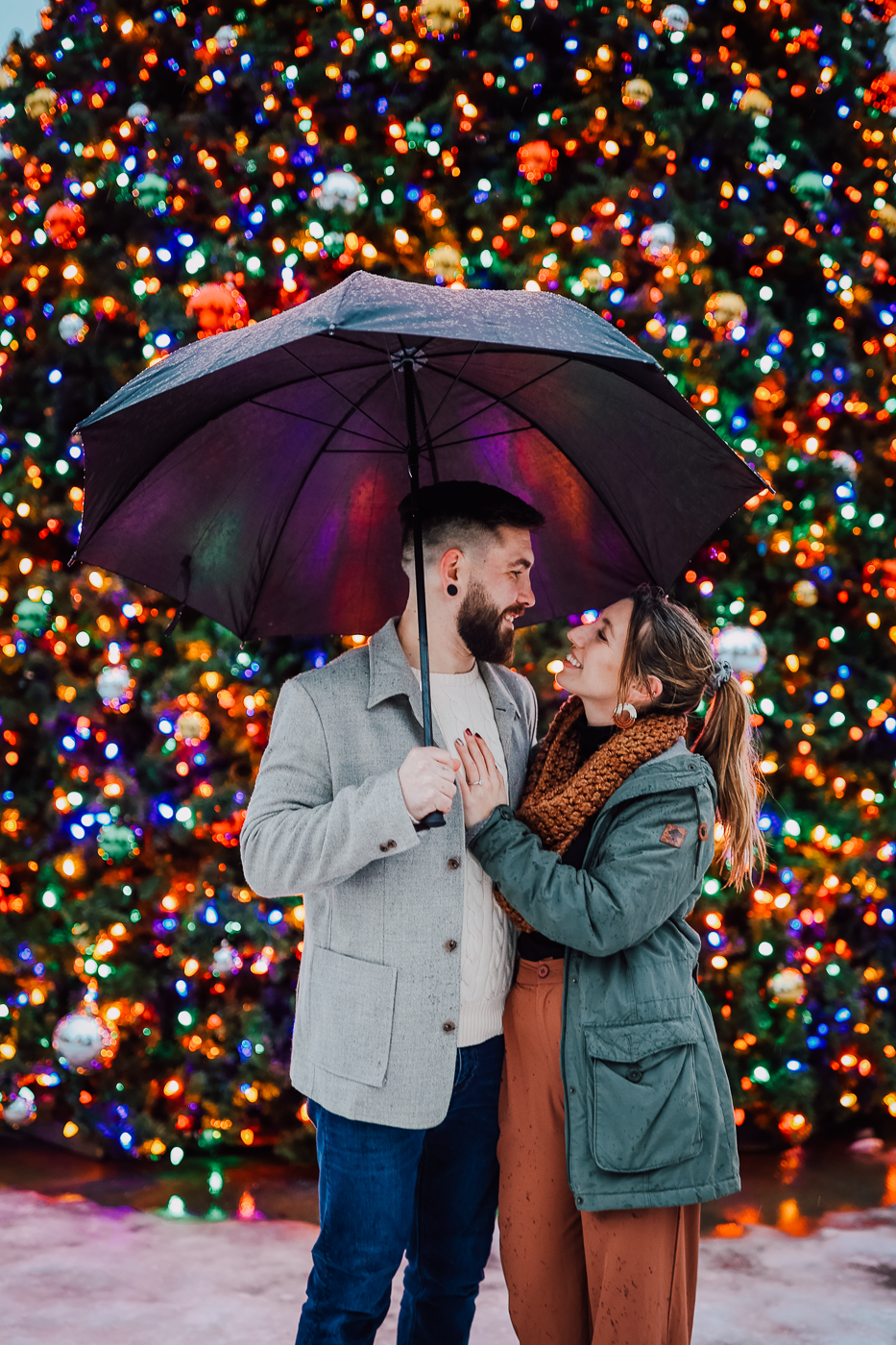  Newly engaged couple embraces in front of a christmas tree in downtown Syracuse after their surprise proposal 