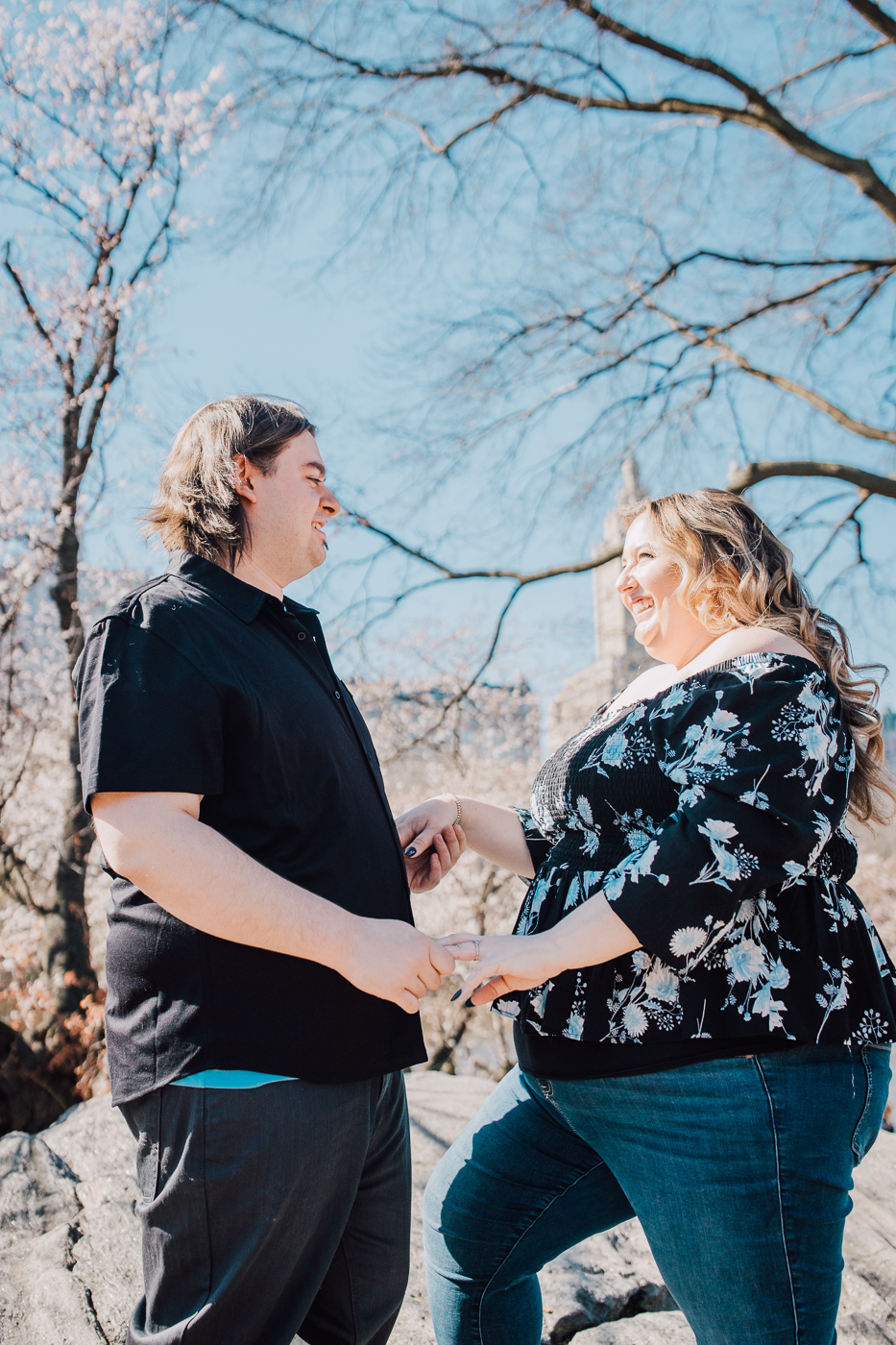  Engaged couple holding hands on top of a large rock in central park during their new york city engagement photos 