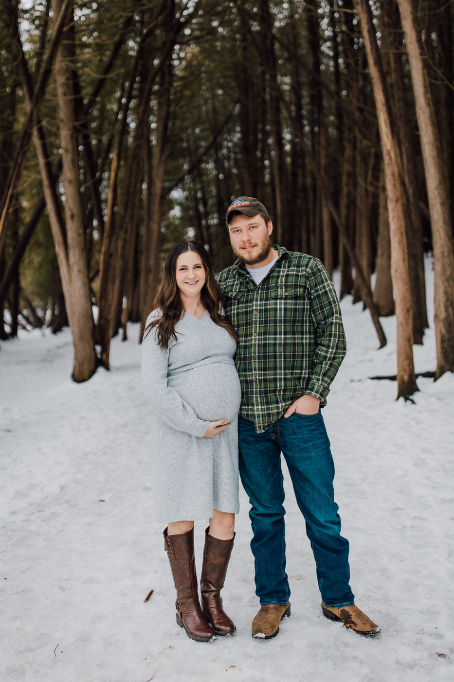  Pregnant woman and her husband take winter maternity photos in the snowy woods at Green Lakes State Park 