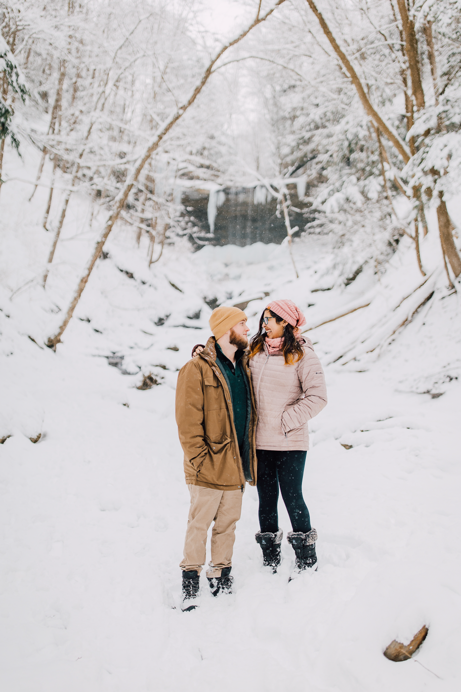  Engaged couple stand in the snow during their adventure photoshoot at Tinker Falls 
