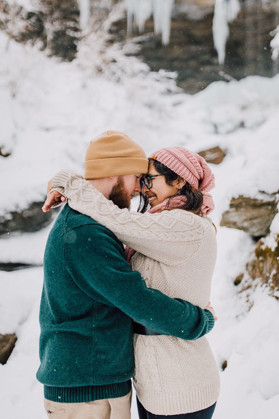  Engaged couple embraces while taking winter wonderland photos with Brittany Juravich at Tinker Falls 