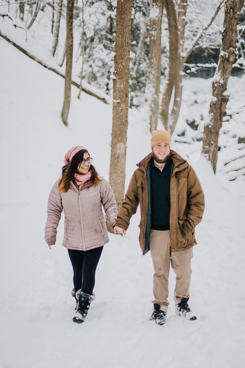  engaged couple walks through the snow at Tinker Falls during an adventure photoshoot with Brittany Juravich   
