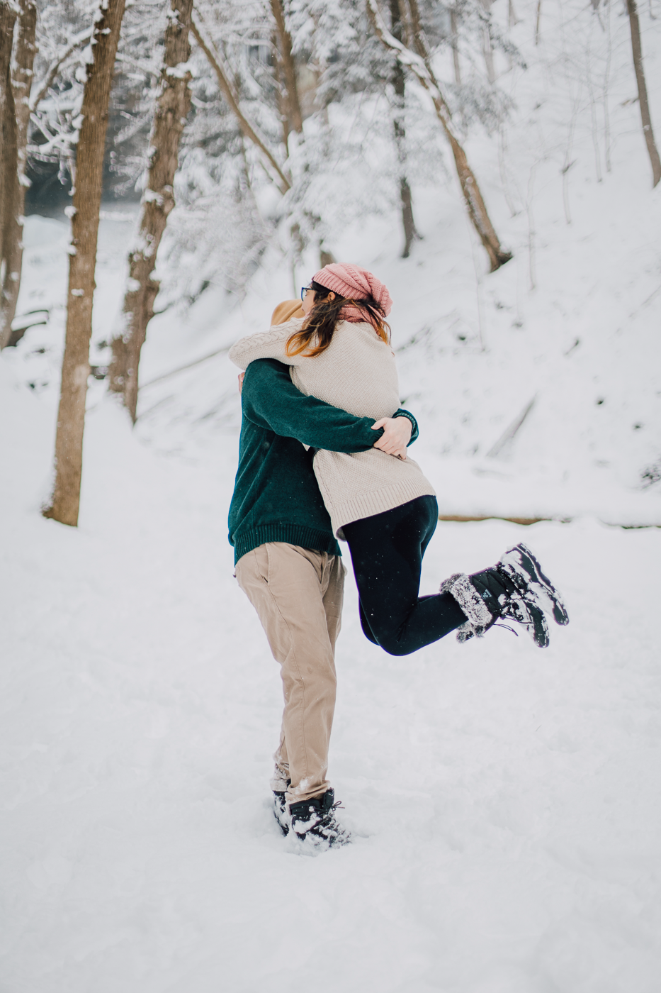  Woman is spun around by her fiance during their winner wonderland photos at Tinker Falls 
