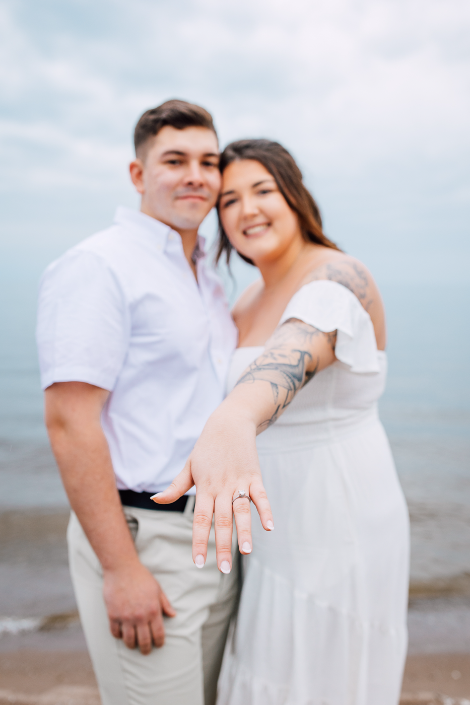  Woman shows off her engagement ring while taking beach engagement photos on a cloudy day at Fair Haven State Park 