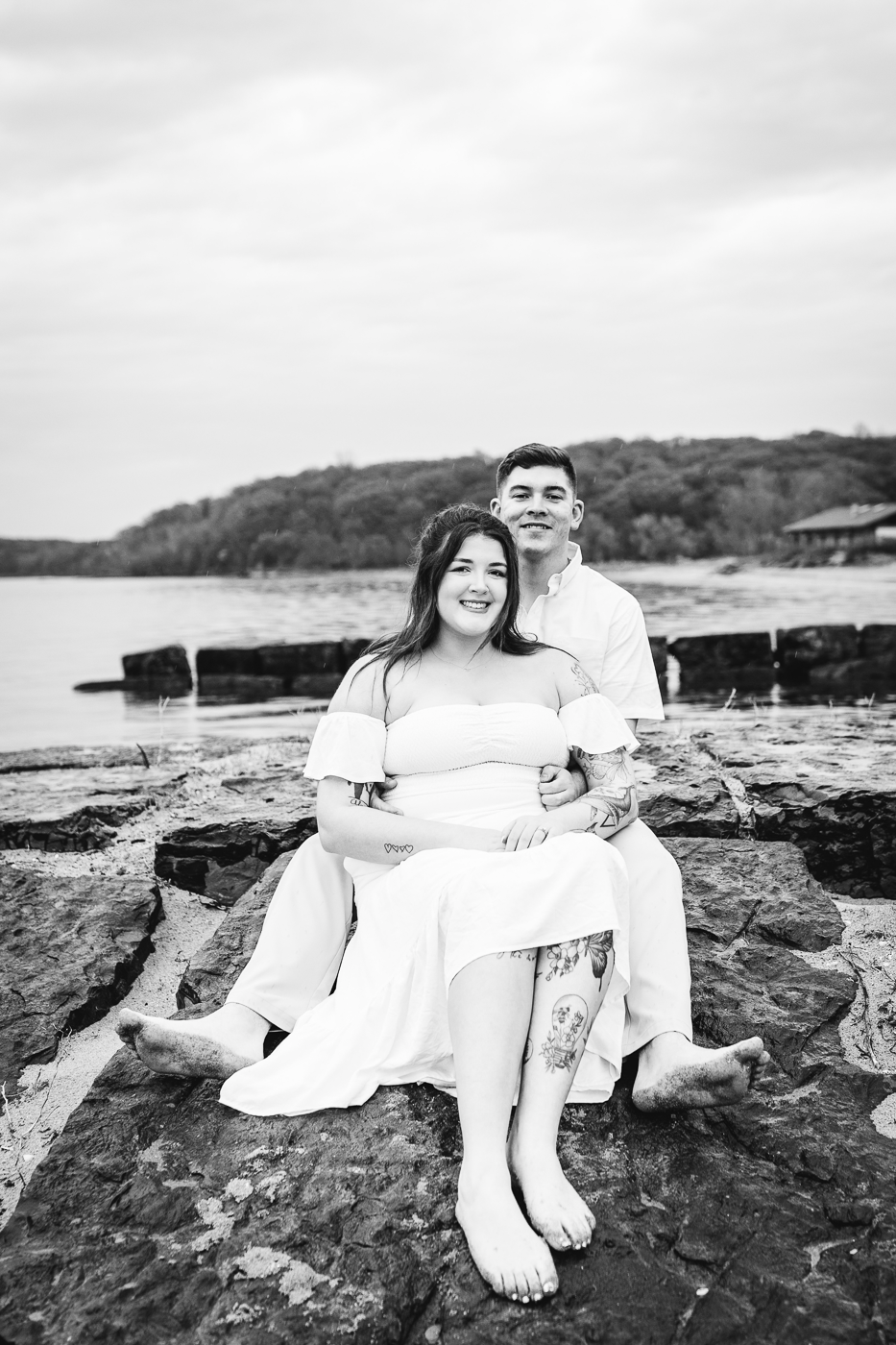  Engaged couple sit on top of a rock at Fair Haven State Park while taking beach engagement photos 