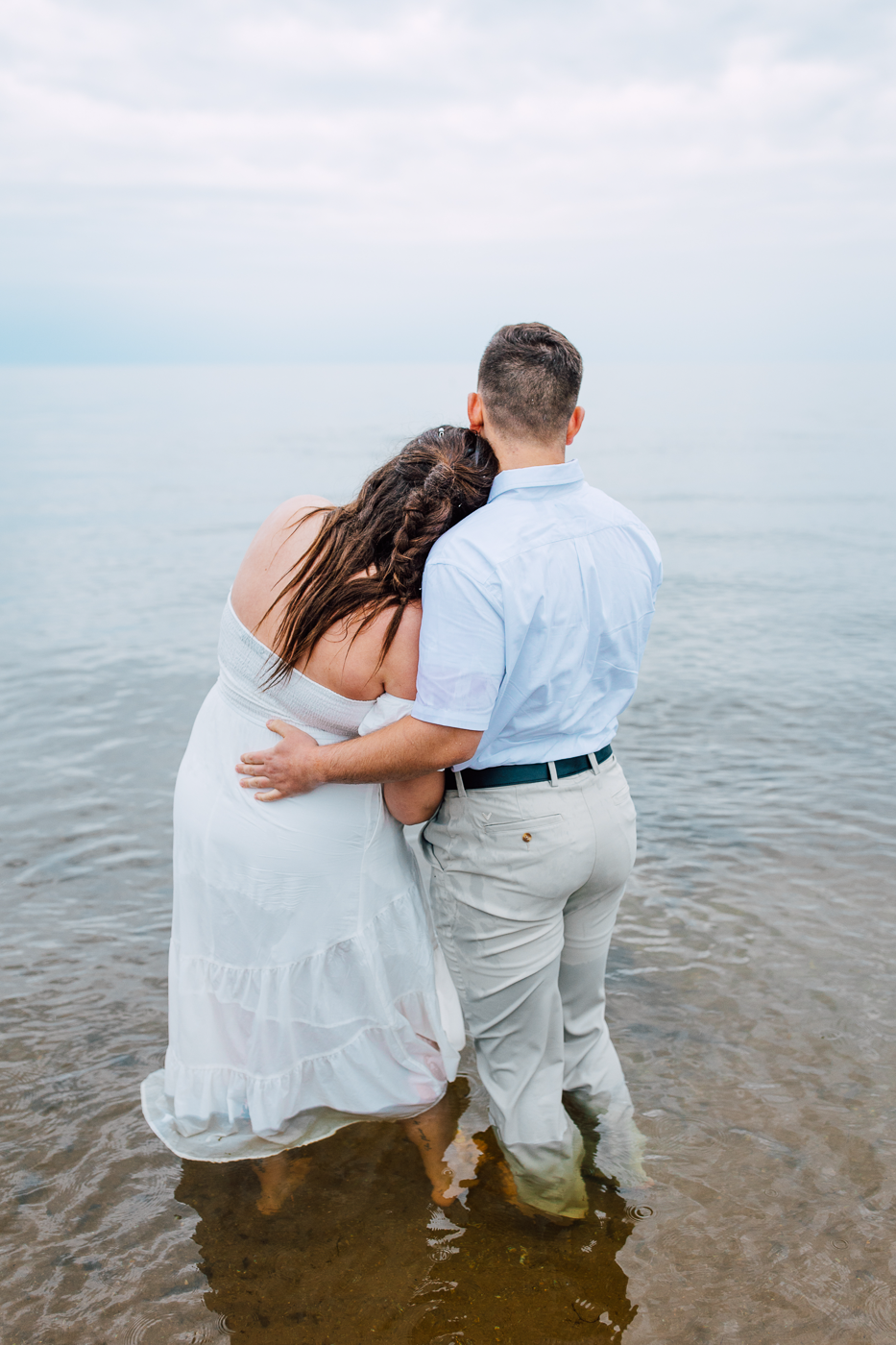  Engaged couple embrace while looking out at Lake Ontario during their engagement session with Brittany Juravich in Central NY 