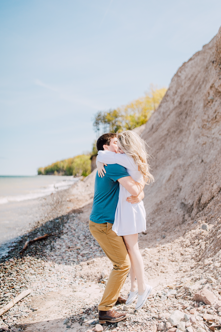  Man lifts his fiance in a big hug during their beach engagement photos in Central NY 