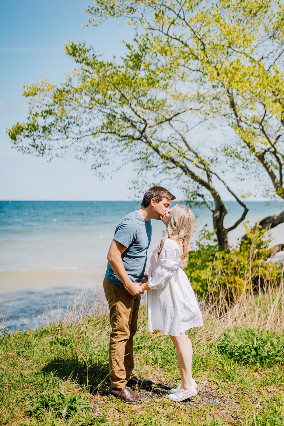  Engaged couple kisses at the top of Sterling Bluffs in Central NY during their beach engagement photos 
