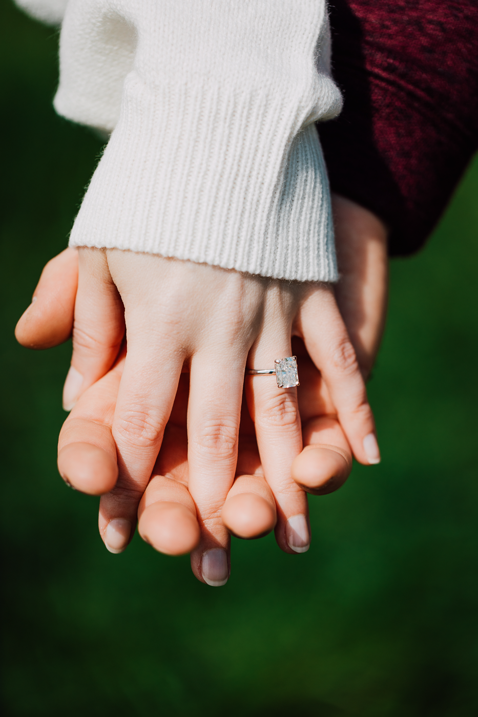  Close up of engaged couple holding hands with the engagement ring prominently displayed 