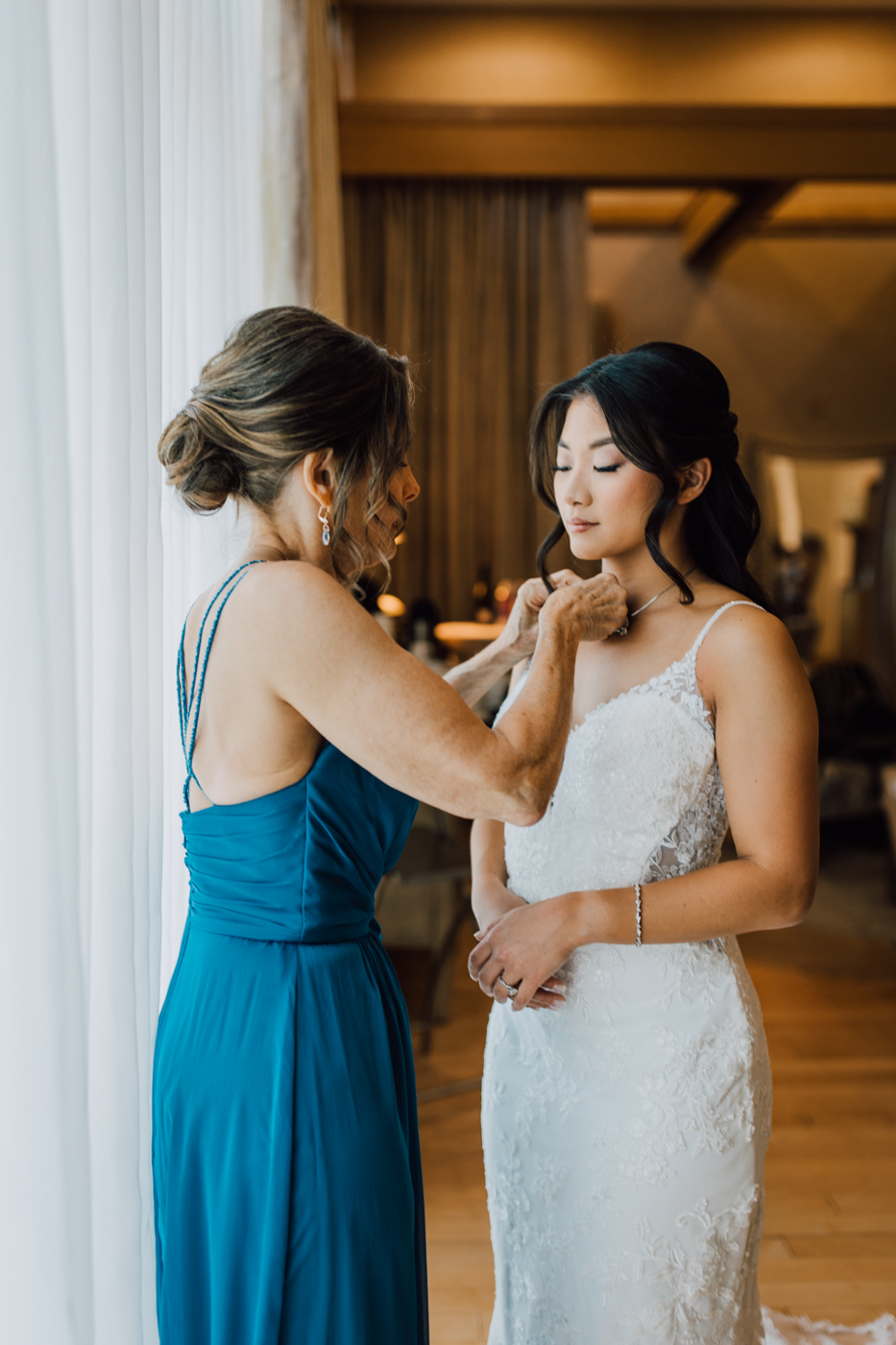  Bride’s mom helps her put on her jewelry before her elegant wedding at Lodge at Turning Stone 