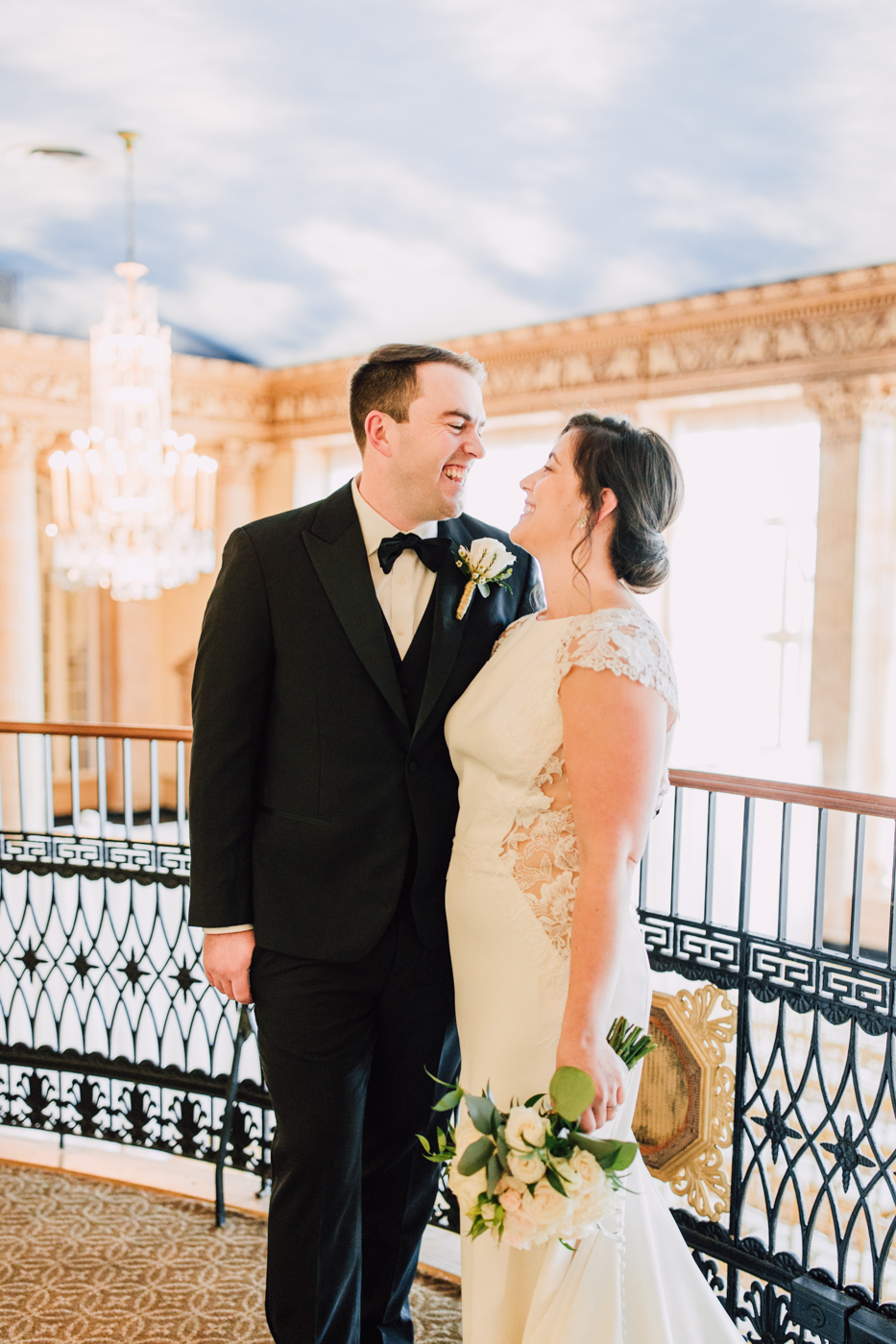  Bride and Groom smile at each other while posing for photos on a balcony at the Marriott Syracuse Downtown 