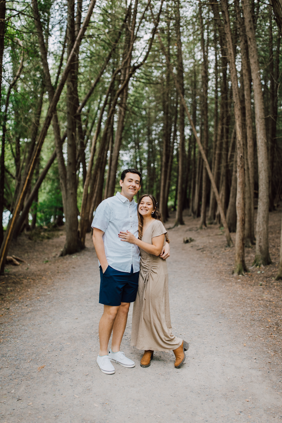  Engaged couple embraces while standing in the forest at Green Lakes State Park for their summer engagement photos 