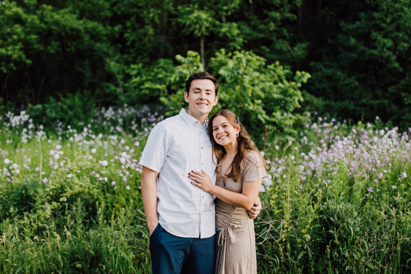  Engaged couple poses in front of wildflowers during their sunset engagement photos at Green Lakes State Park 