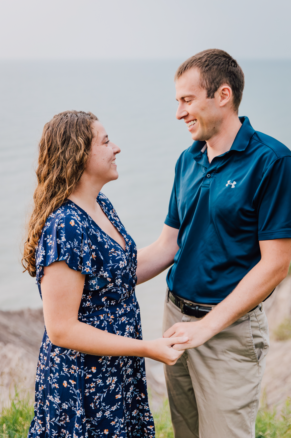  Engaged couple hold hands during their summer engagement photos at the top of the Oswego Bluffs in Central NY 