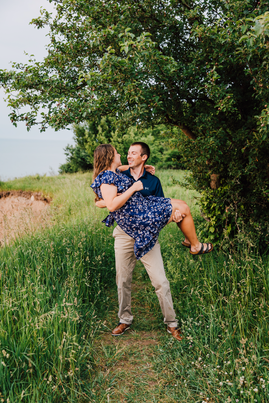  Man picks up his fiance during their summer engagement photos in Oswego NY   