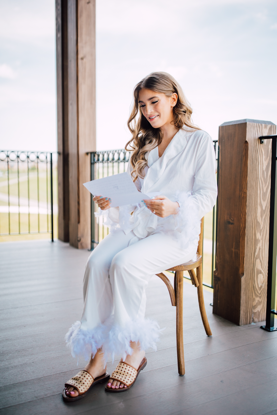  Bride wears white feathered pajamas while reading a letter from her Groom before their traditional wedding at Timber Banks in central NY 