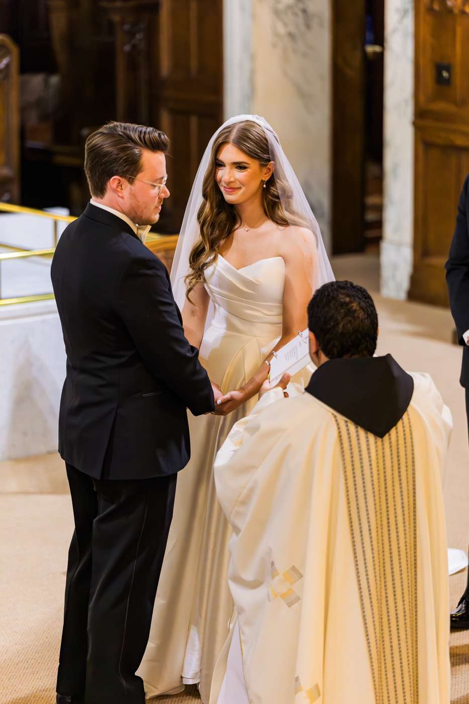  Bride smiles at her Groom while they exchange vows during a catholic mass at Assumption Church in Syracuse NY 