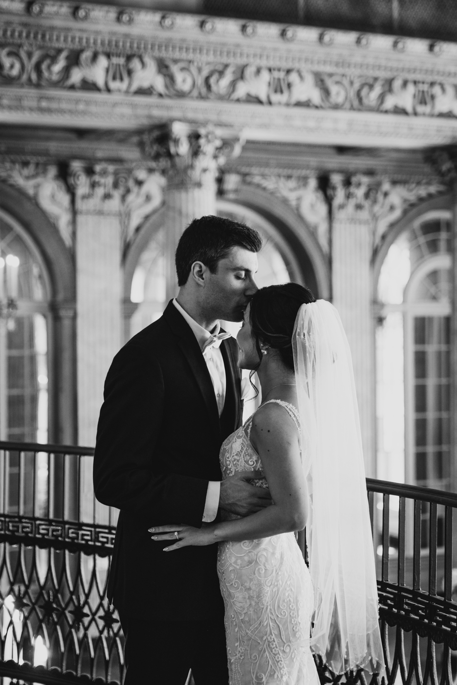  Groom kisses his Bride on the forehead before their elegant ballroom wedding in downtown Syracuse 