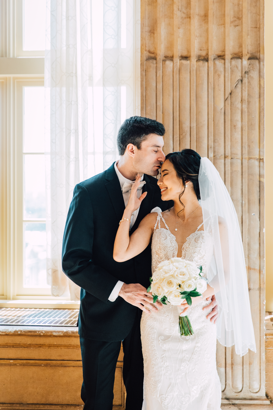  Bride and Groom pose for photos in the ballroom of Hotel Syracuse before their elegant wedding 