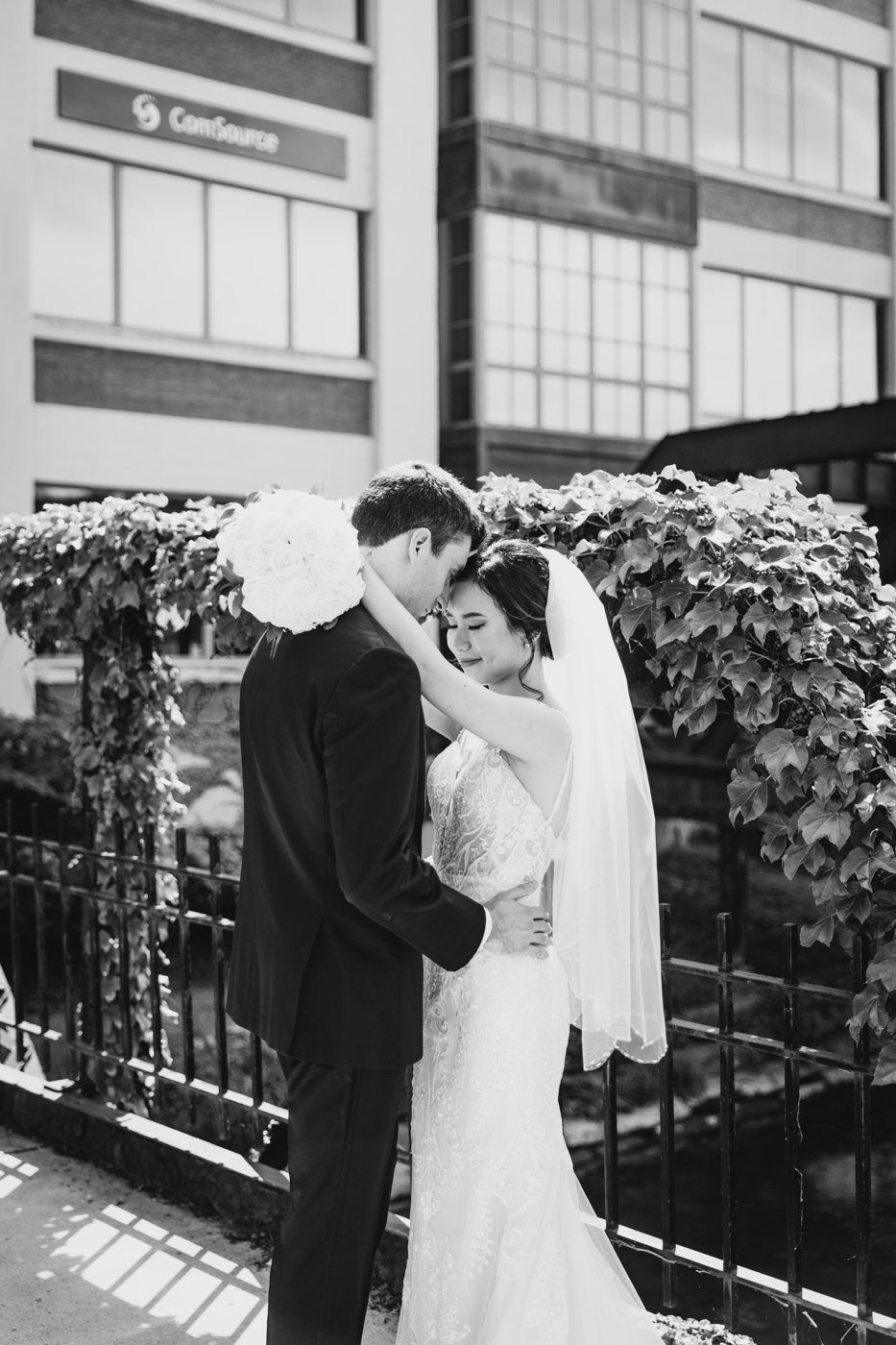  Bride and Groom embrace on a bridge in downtown Syracuse while taking wedding photos on their wedding day 