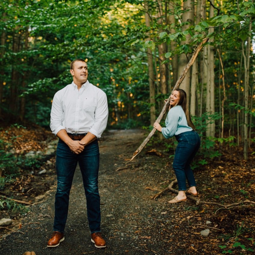  Woman pretends to whack her fiance with a stick while taking forest photos with Brittany Juravich in Central NY 