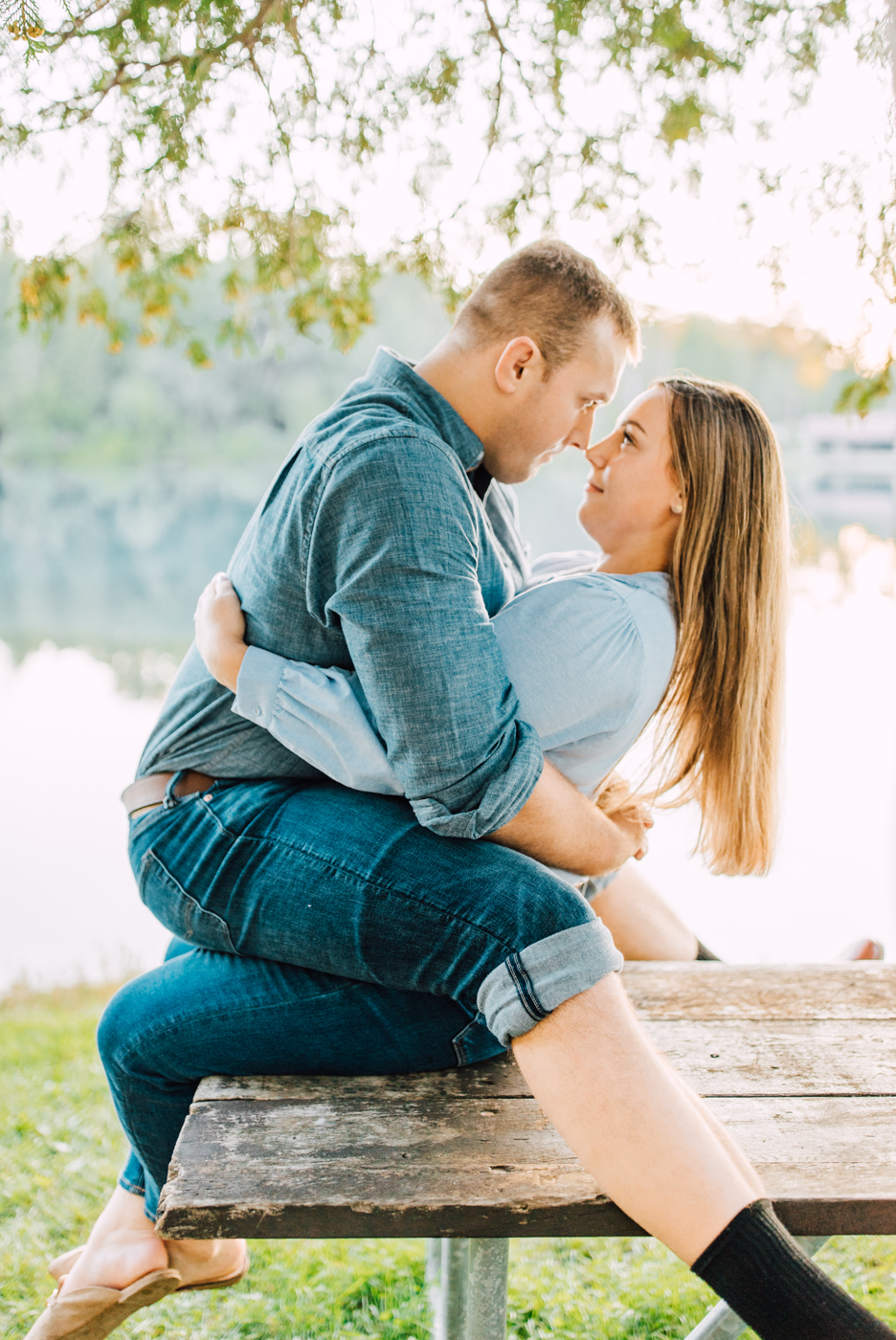  Engaged couple stare into each others eyes while straddling on a picnic table during their funny engagement photos 