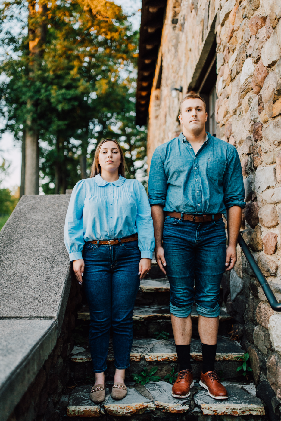  Engaged couple stand awkwardly on a stone staircase at Green Lakes State Park during their funny engagement photos 