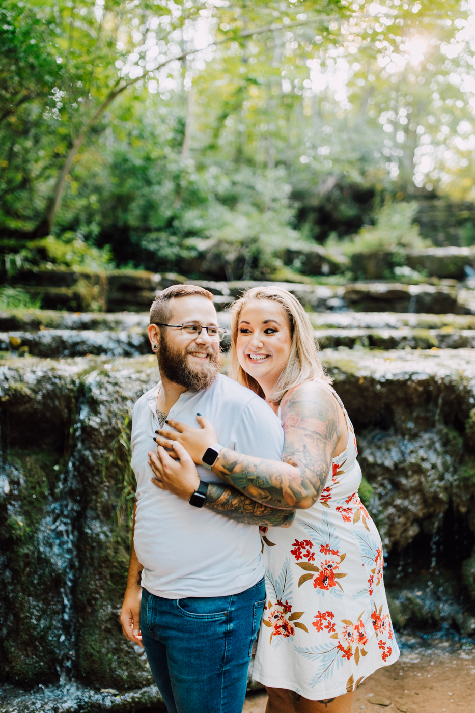  Woman hugs her fiance from behind during their adventure photoshoot at Three Falls Woods 