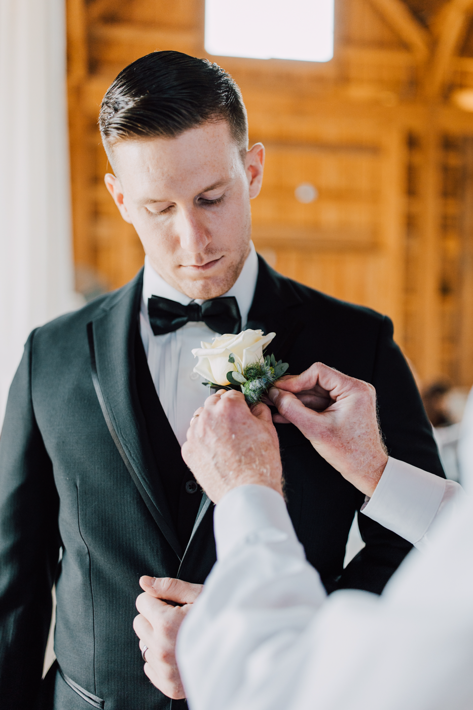  Groom has his boutonniere pinned onto his tuxedo jacket before his vow renewal in Central NY 