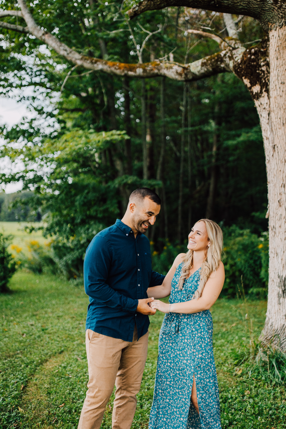  Engaged couple laugh while holding hands during their timeless engagement photos in Oswego NY 