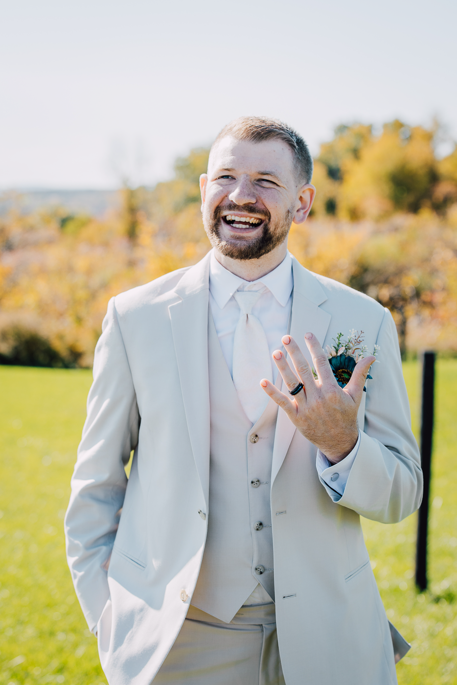  Groom laughs as he holds up his hand to show off his wedding ring 