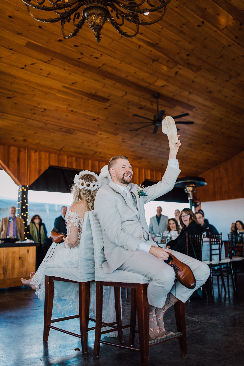  Groom holds up a slipper while playing the shoe game at his wedding reception 