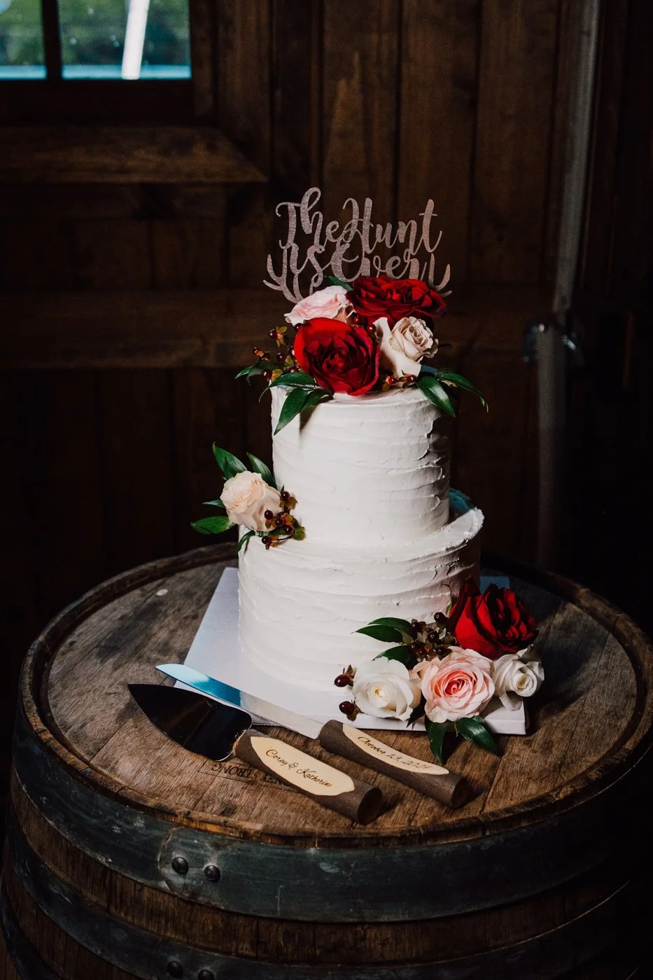  Two tier wedding cake sits atop a barrel during a barn wedding reception in Central NY 