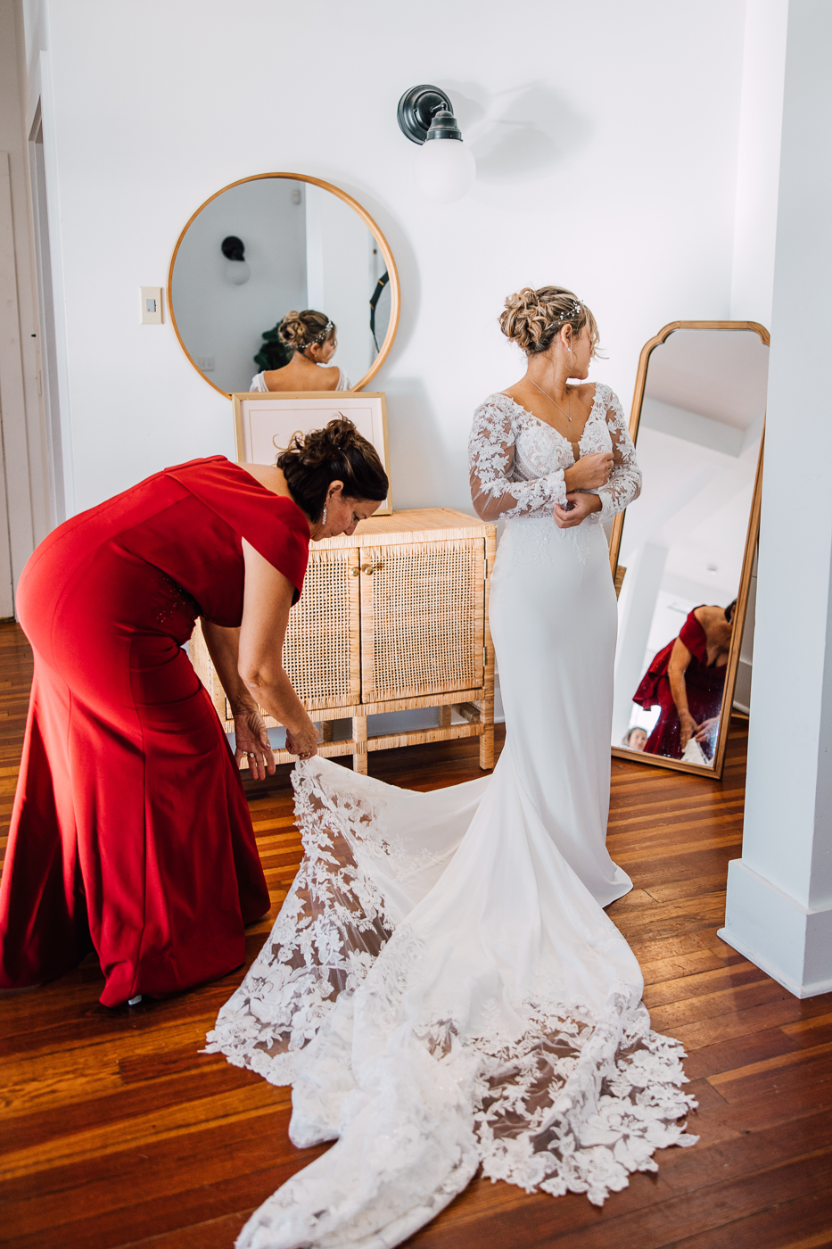  Bride looks at herself in the mirror as her mom straightens her lace train at her Emerson Park Pavilion wedding 