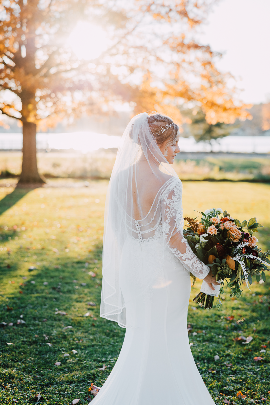 Bride shows off the back of her lace dress while taking sunset wedding photos overlooking the fingerlakes 