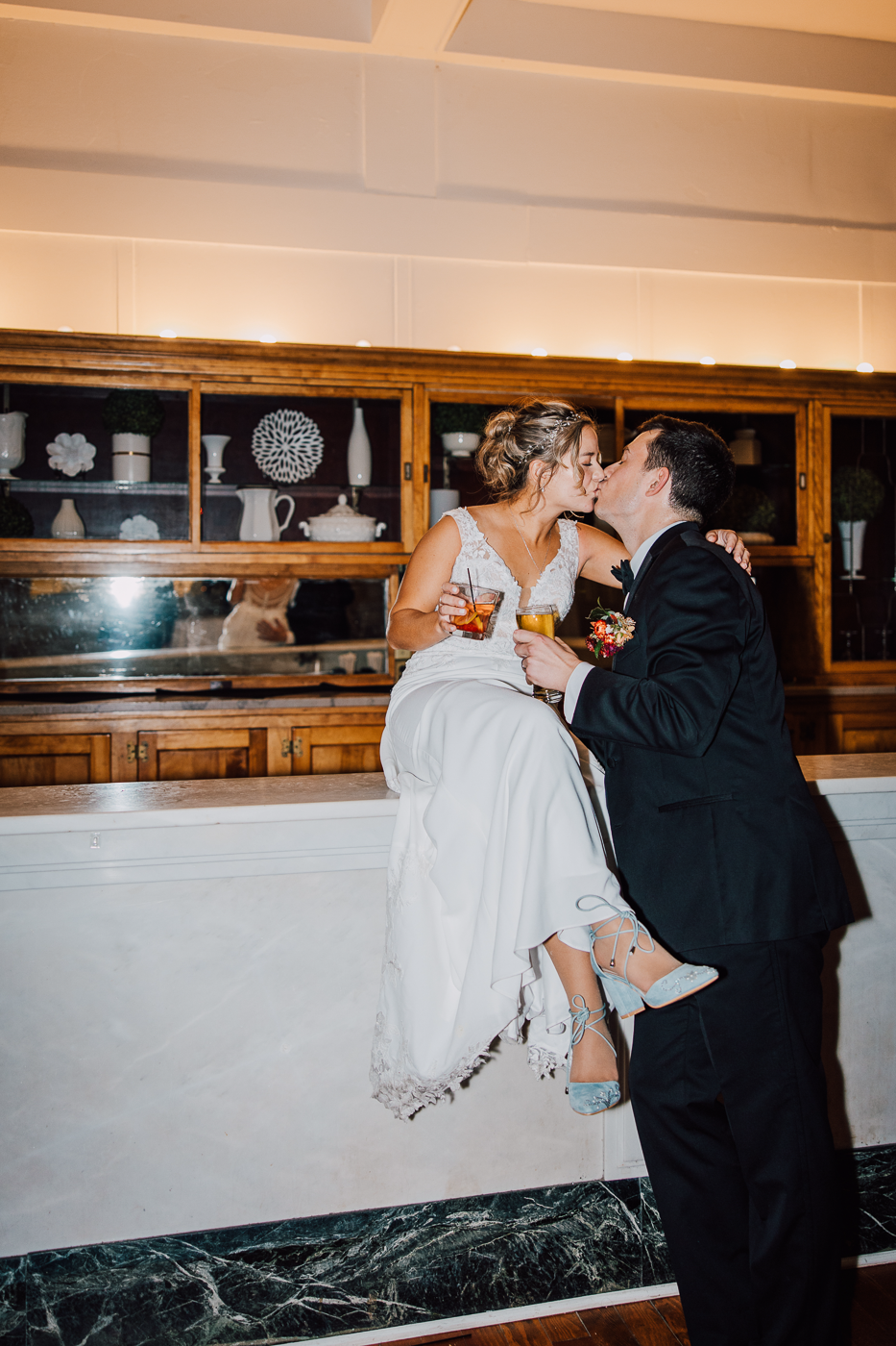  Bride and Groom kiss as she sits on the bar at Emerson Park Pavilion   
