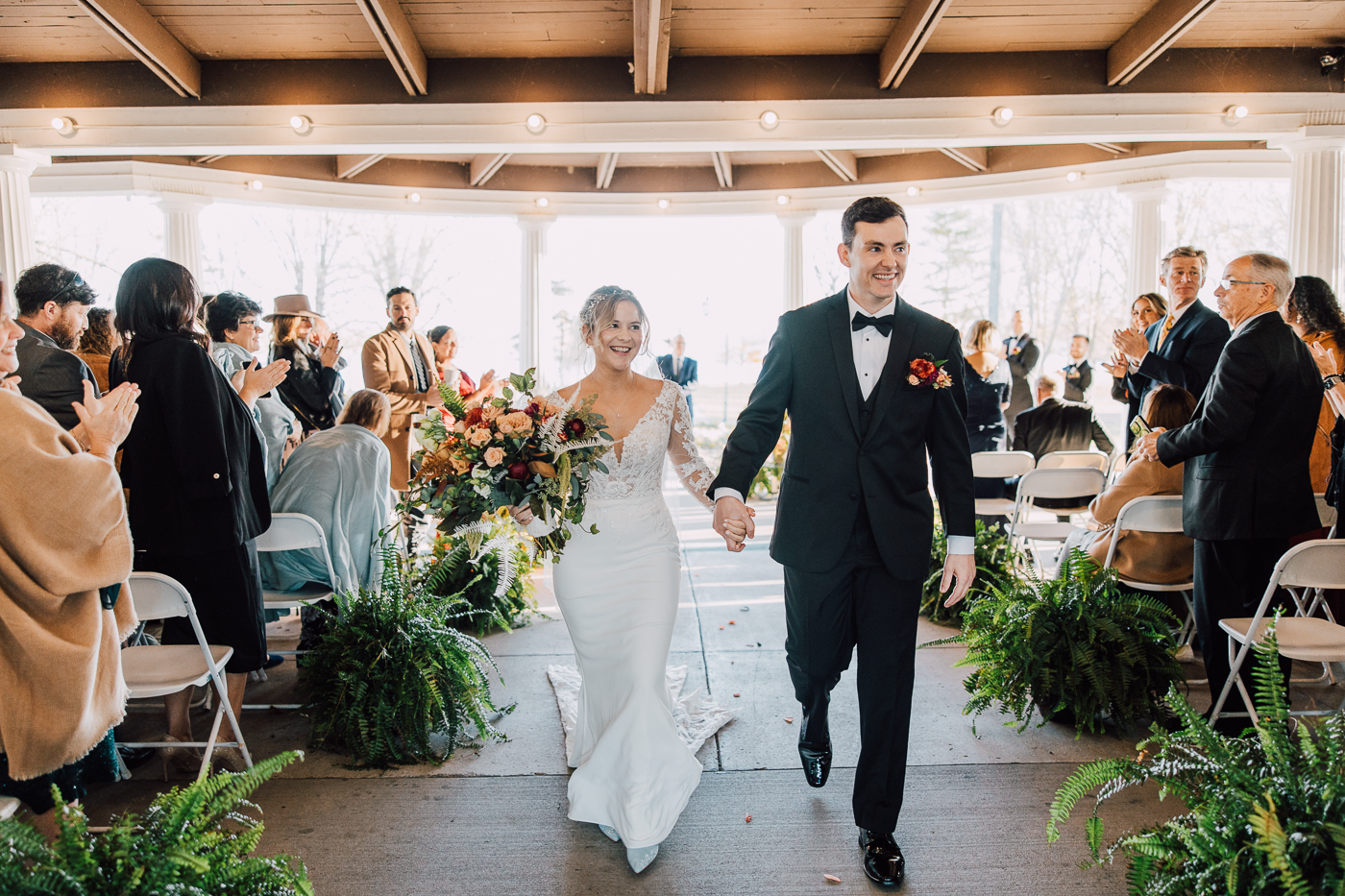 Bride and Groom smile and walk hand-in-hand down the aisle after their wedding ceremony